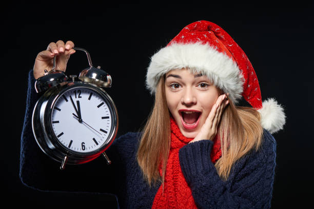 istock Surprised girl in Santa hat with alarm clock 871320254