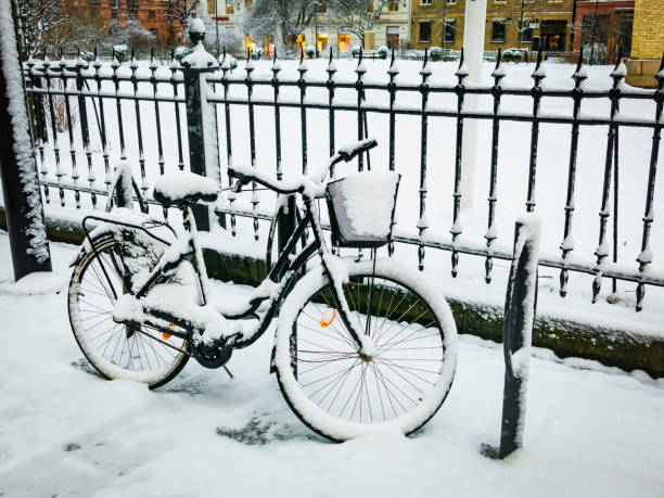 Snowy bike parked against a black steel fence a winters day