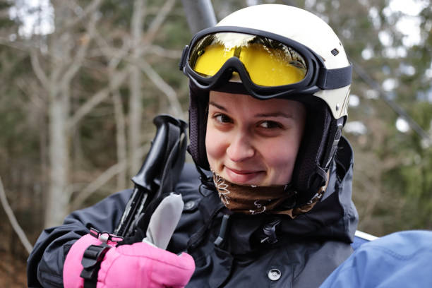 Young woman in ski outfit shows thumbs up Happy young woman in ski outfit rides at the cableway with Ski lift and shows thumb up. Close-up thumbs up for skiing stock pictures, royalty-free photos & images