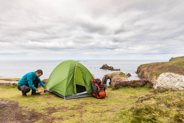 istock Man set up a tent on top of cliffs 871339282
