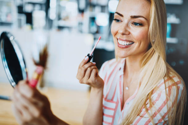 istock Young beautiful woman applying make up using small mirror 871339494