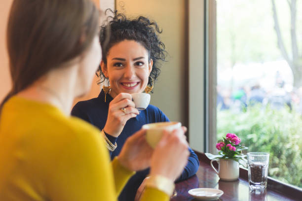 istock Two women in a cafe smiling and drinking coffee together 871342720