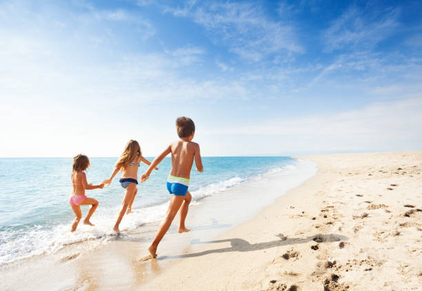 istock Kids running along beach during summer vacation 871342886