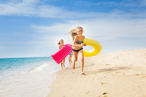 Happy kids having a race on sunny beach in summer Happy kids running with swimming tools on sandy beach in summer game resort pictures stock pictures, royalty-free photos & images