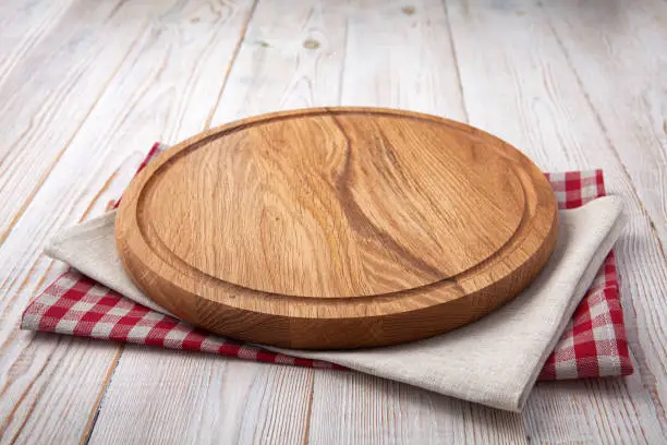 Photo of Pizza board with a napkin on white wooden table. Top view mock up