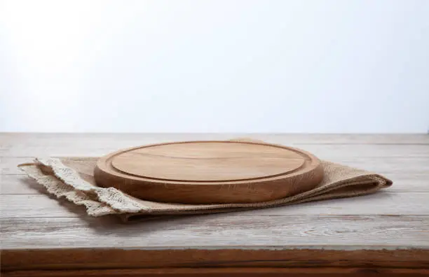 Photo of Pizza board, canvas napkin with lace on wooden table. Top view mock up