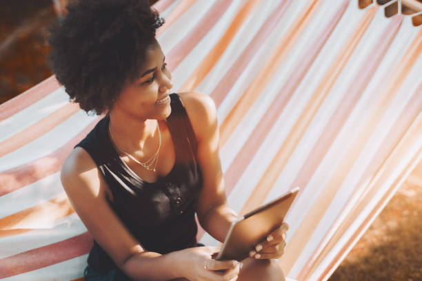 istock Black girl in hammock with digital pad 871361442