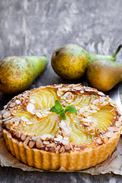 Delicious  cake with half poached pears and almond flakes Delicious  cake with half poached pears and almond flakes pear dessert stock pictures, royalty-free photos & images