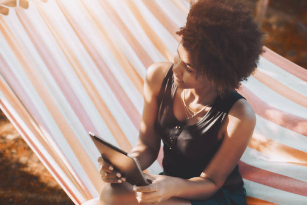 istock Biracial lady on hammock in garden with digital pad 871361820