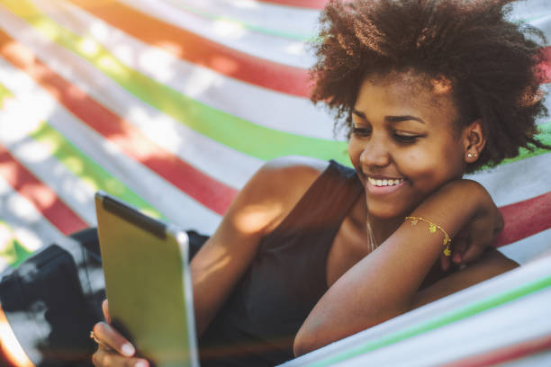 istock Black girl in hammock with digital pad 871362002