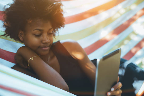 istock Black girl in hammock with digital pad 871362180