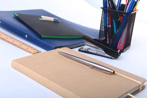 Colorful notebooks and office supplies on white table