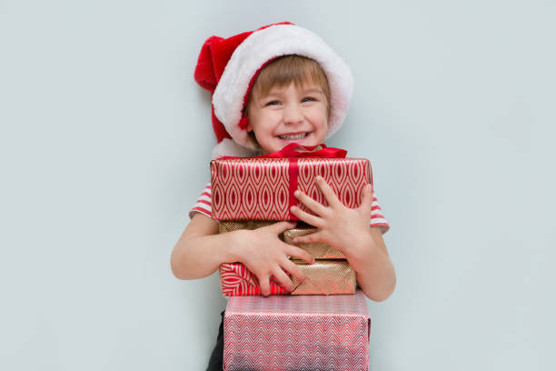 Happy child in Santa red hat holding Christmas present. Christmas time. stock photo