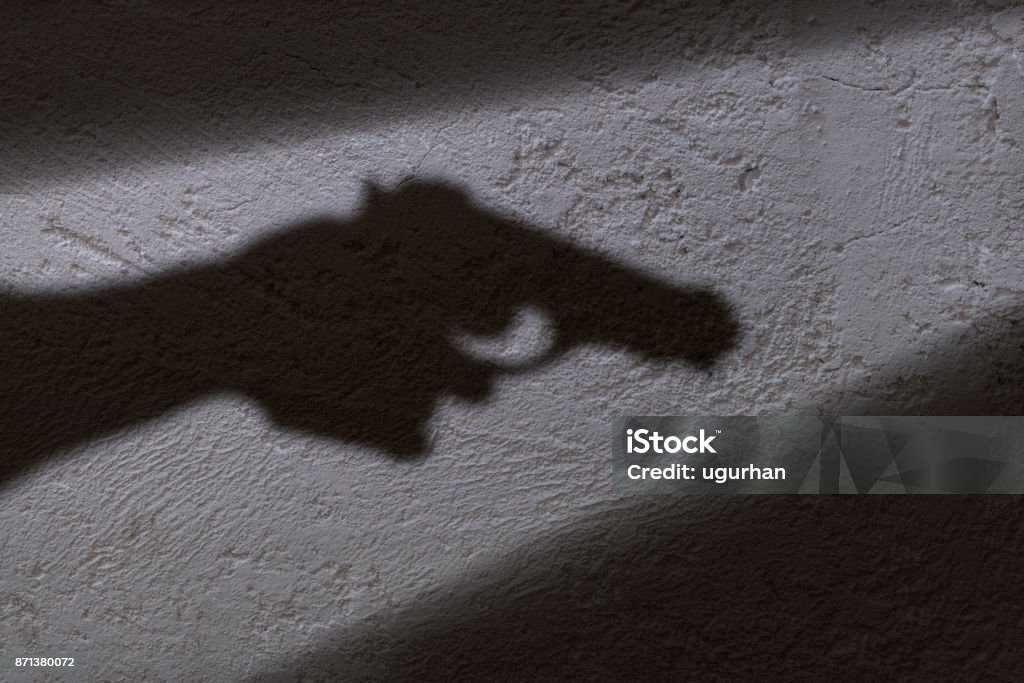 Shadow and gun A shadow of a hand holding a gun in his hand. Gun Stock Photo