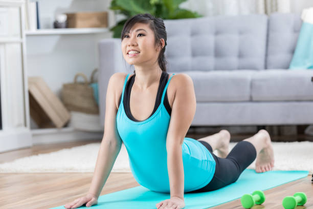 istock Young woman performs cobra pose during yoga at home 871381528
