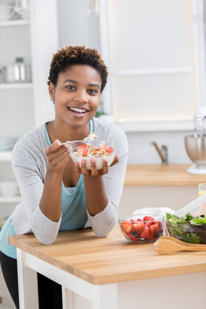istock Young woman smiles for camera while eating yogurt parfait 871381554