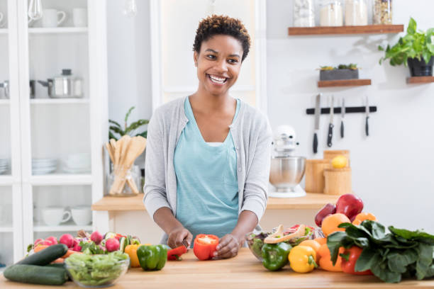 istock Cheerful woman slices vegetables in kitchen 871381570