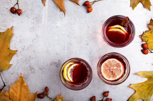 Hot red tea with lemon on light gray table with copy space viewed from above, delicious autumn mulled wine drink