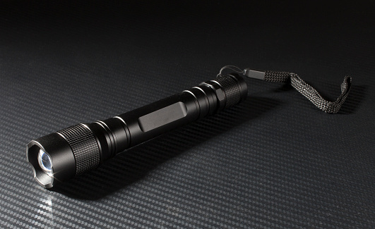 Tactical flashlight with lanyard on a graphite background