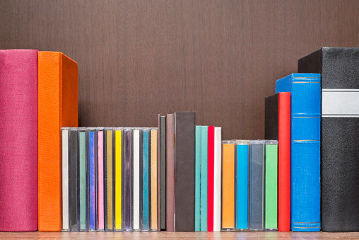 stack of colorful books, cd and cassettes in the book self