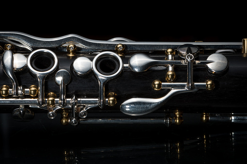 Details of a clarinet with silver keys and golden sockets black background