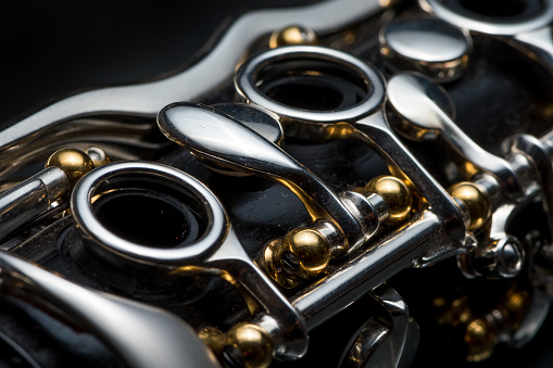 Details of a clarinet with silver keys and golden sockets black background