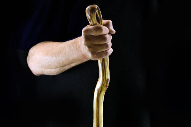 istock Hand with staff or walking stick    black background 871410396
