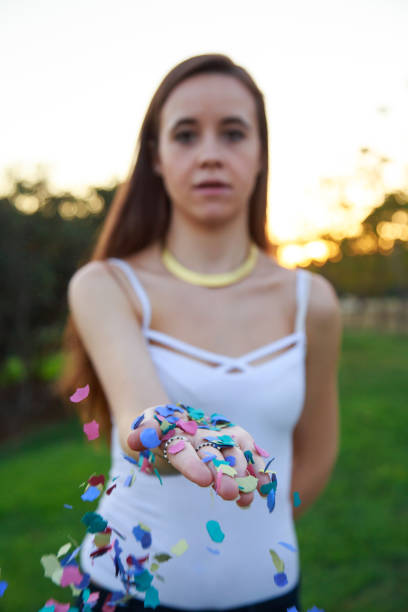 istock Young woman throwing confetti with her hand 871414232