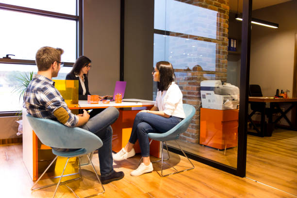 young couple getting advice in office from beautiful business woman - bank bank teller customer banking imagens e fotografias de stock