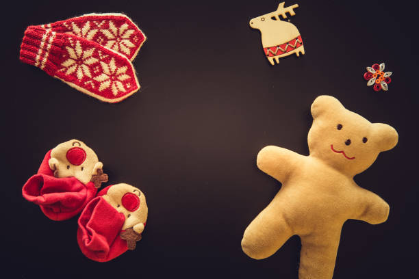 Baby gloves, bootees and a Teddy bear on black