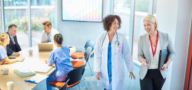 medical business relationship a businesswoman chats with a doctor as they leave a boardroom meeting in a hospital healthcare management stock pictures, royalty-free photos & images