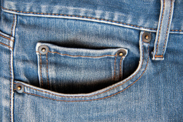 Tiny front pocket on denim pants, close up.