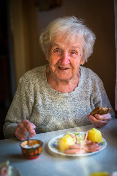 istock An elderly woman eating lunch sitting at the table. 871437254