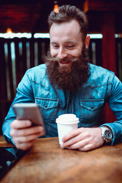 istock Handsome Smiling Hipster Person Texting and Drinking Coffee 871438644