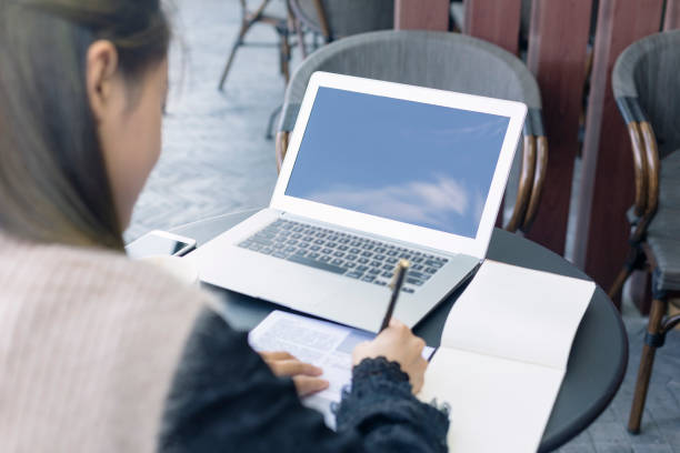 istock young woman making notes while looking at the laptop 871438718