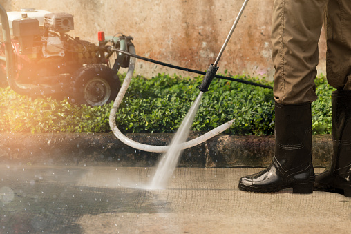 Worker cleaning driveway with gasoline high pressure washer ,professional cleaning services.