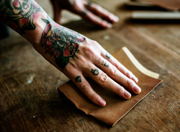 istock Hands with tattoo using sandpaper on a wood 871465056