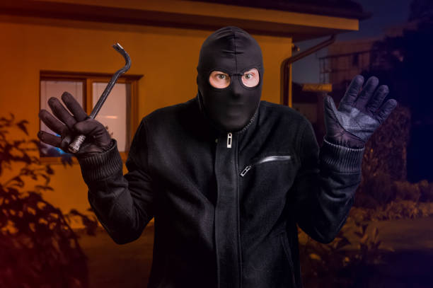 istock Arrested masked thief in balaclava with crowbar and raised arms 871475238