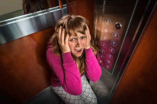 Photo of Shocked woman with claustrophobia in the moving elevator