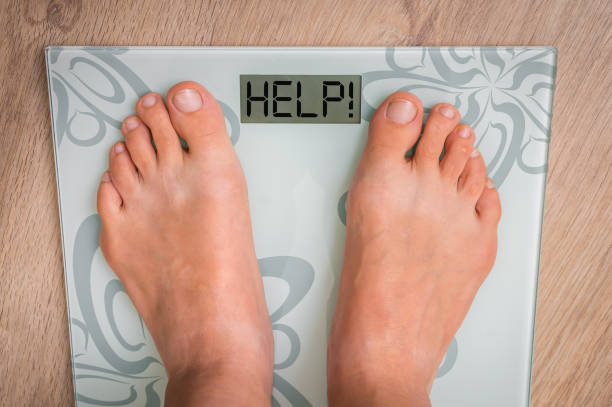 istock Female feet on personal scales with word HELP! 871475752
