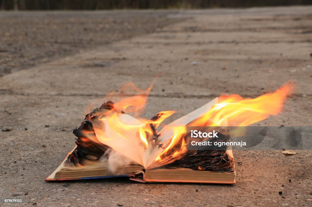 book with burning pages on a concrete surface the book lies on the asphalt - the pages are burning with bright fire Book Stock Photo