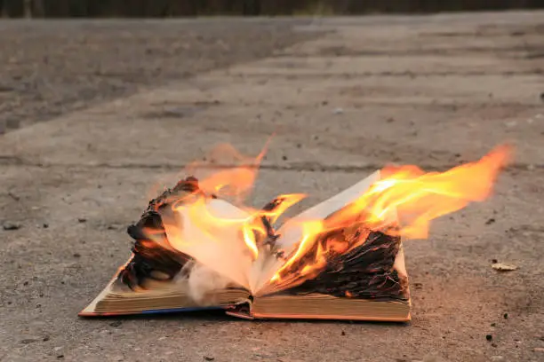 Photo of book with burning pages on a concrete surface