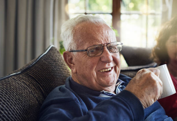 istock Smiling senior man with coffee cup, his wife in background 871482206