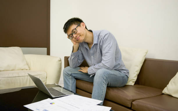 istock Stressed Asian businessman using a smartphone in living room at night 871483466