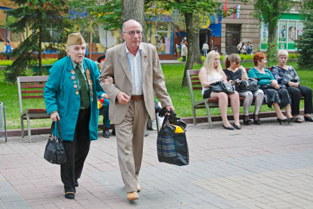 world war ii veteran accompanied by relative on victory day celebration on the avenue of heroes in volgograd - veteran world war ii armed forces military imagens e fotografias de stock