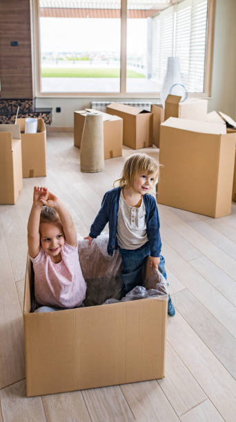 istock Playful kids having fun in carton box while relocating in new home. 871489878