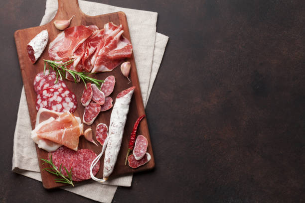 Salami, ham, sausage, prosciutto Salami, sliced ham, sausage, prosciutto, bacon. Meat antipasto platter on stone table. Top view with copy space sliced salami stock pictures, royalty-free photos & images