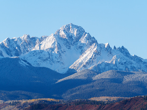 Close up of snow covered Sneffels Range in a bright daylight blue sky in fall foliage autumn season near Ridgway, Colorado, USA.