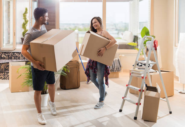 istock Young happy couple communicating while carrying cardboard boxes in their new apartment. 871506140