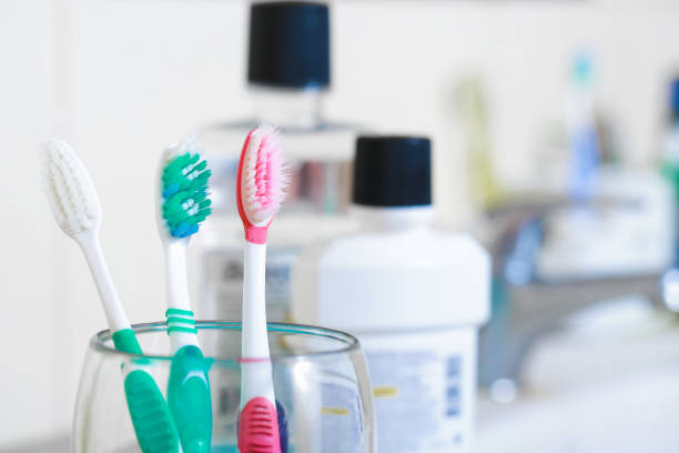Toothbrushes in glass on table in bathroom.